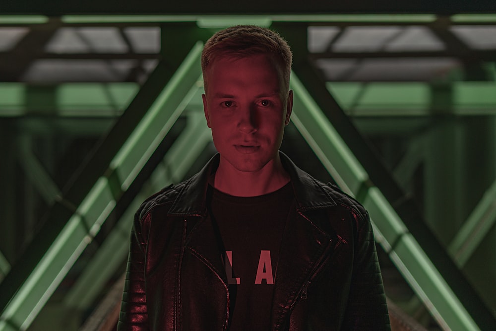 man in black leather jacket standing near glass window