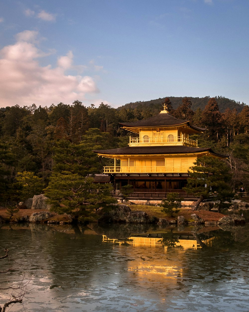 a building sitting on top of a lake next to a forest