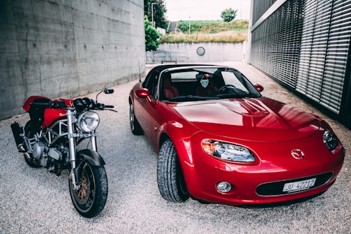 red ferrari car parked beside gray concrete wall