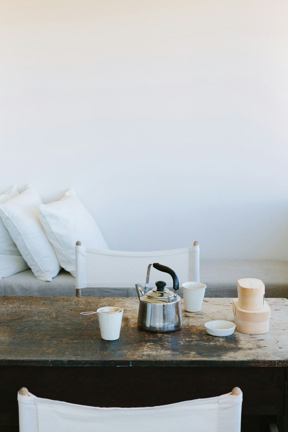 stainless steel kettle beside white ceramic mug on brown wooden table