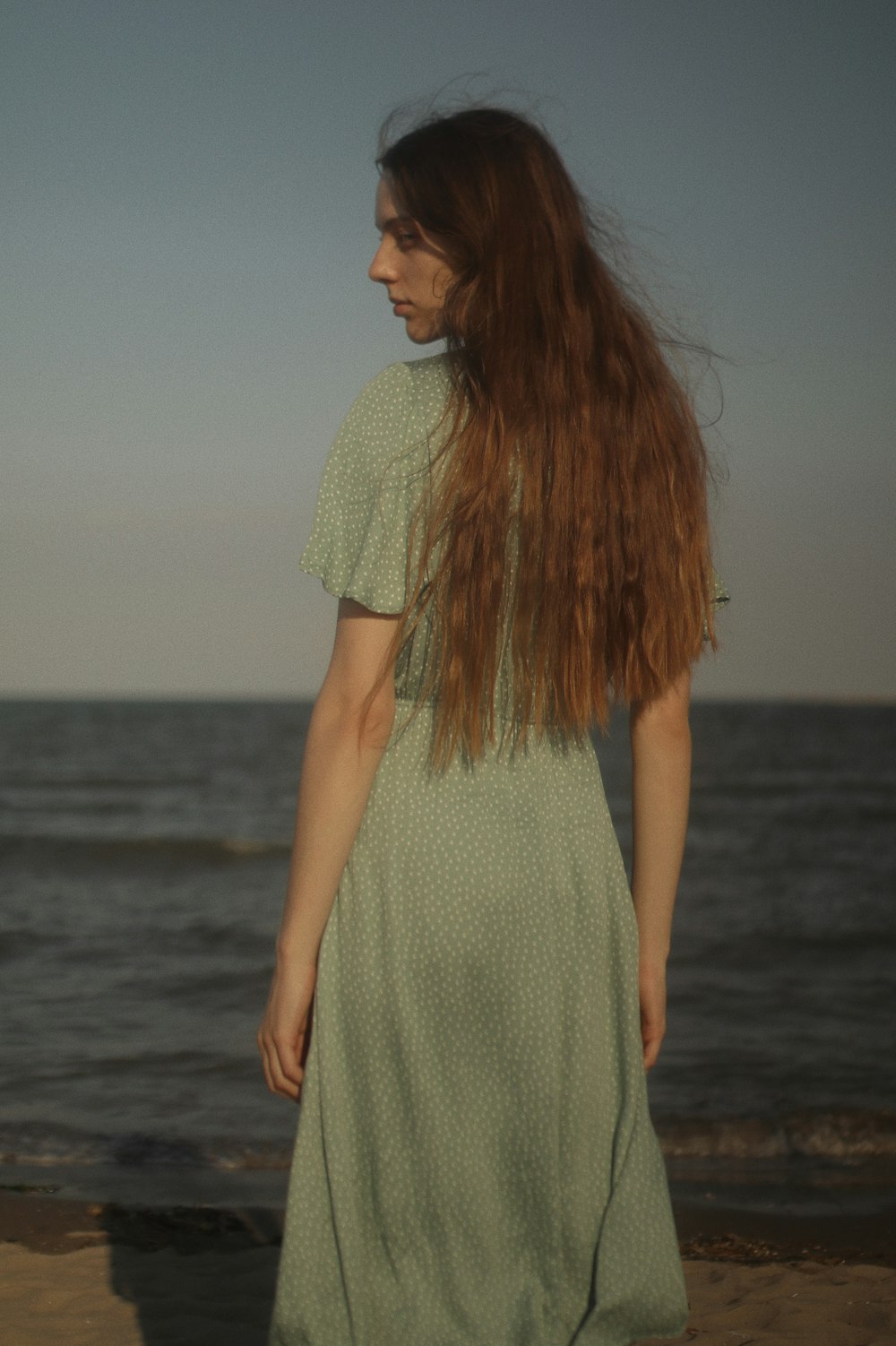 woman in green dress standing on beach during daytime