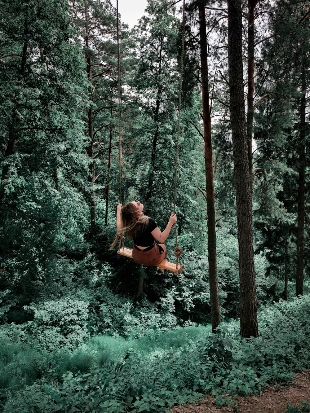 woman in brown long sleeve shirt sitting on brown tree branch during daytime