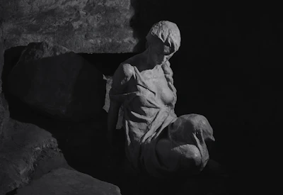 Elegant stone sculpture of a seated figure bathed in soft gallery lighting.