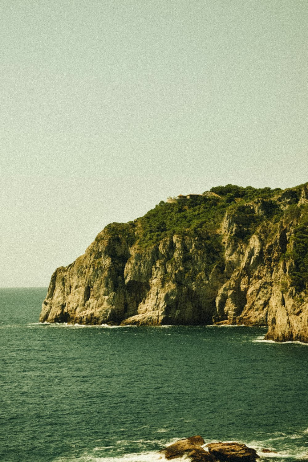 brown and green rock formation on sea during daytime