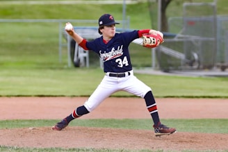 man in blue and white jersey shirt and white pants holding baseball bat