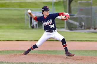 man in blue and white jersey shirt and white pants holding baseball bat