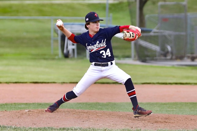 man in blue and white jersey shirt and white pants holding baseball bat