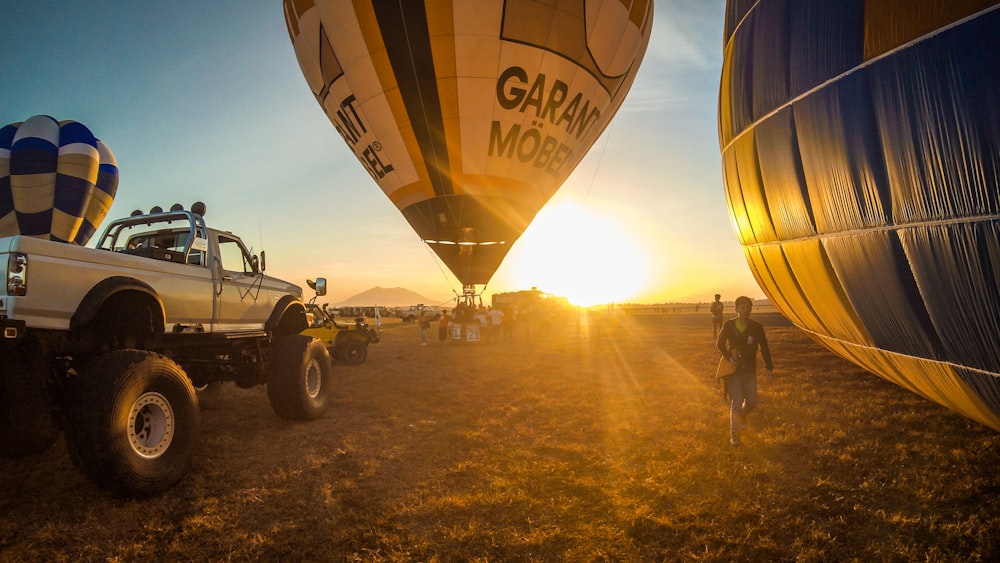 people standing near hot air balloons during sunset