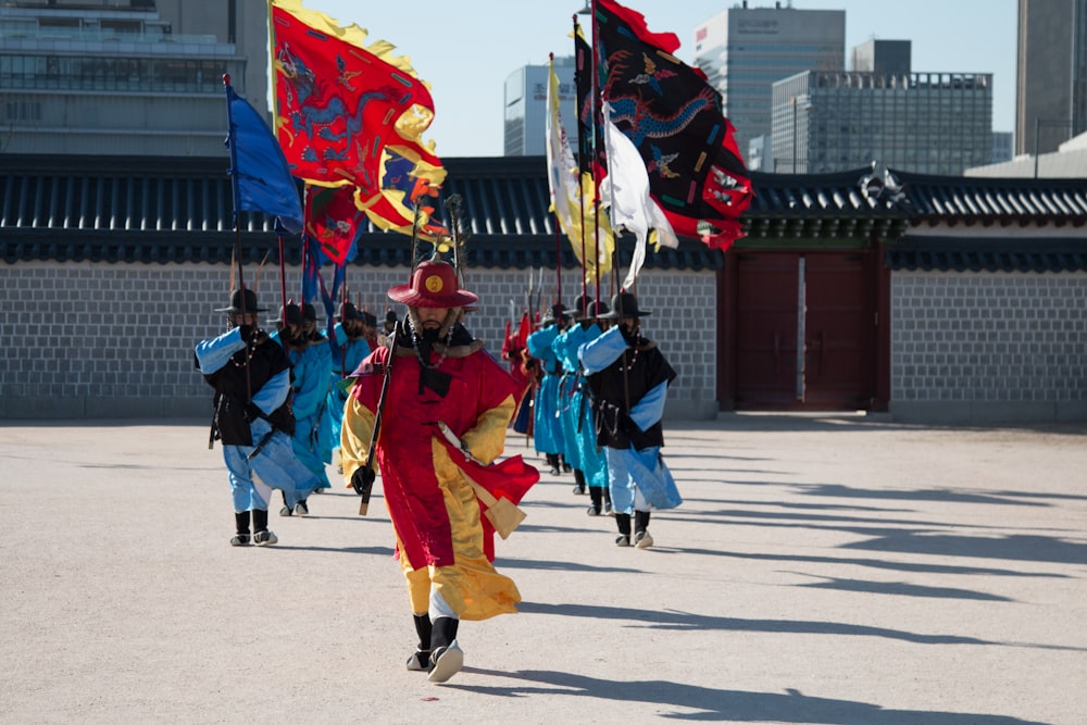 people in blue and red traditional dress holding flags during daytime