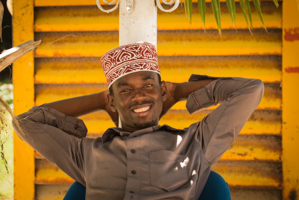 man in blue dress shirt and brown pants wearing white and red knit cap