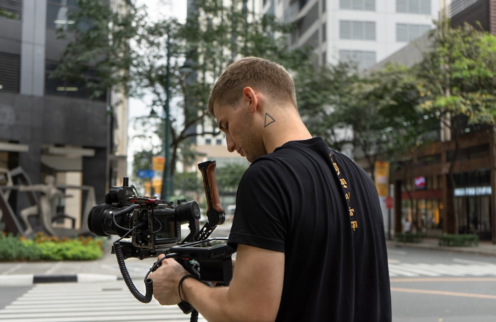 man in black t-shirt holding black video camera