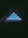 A triangular attic window frames a scenic view of distant blue mountains under a clear sky. The interior of the attic is dark, creating a stark contrast with the bright landscape outside.