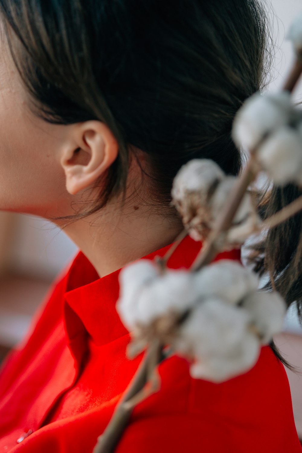 woman in red shirt with white flowers on ear