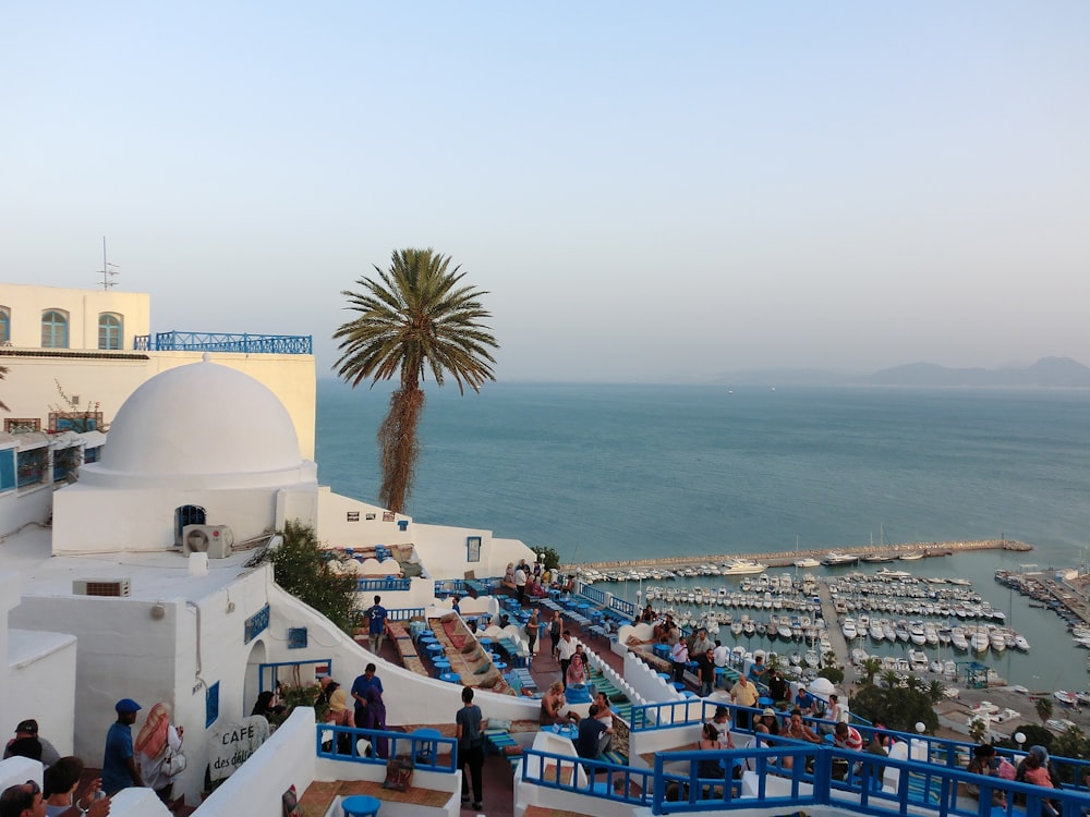 Personnes sur la plage près d’un bâtiment en béton blanc pendant la journée