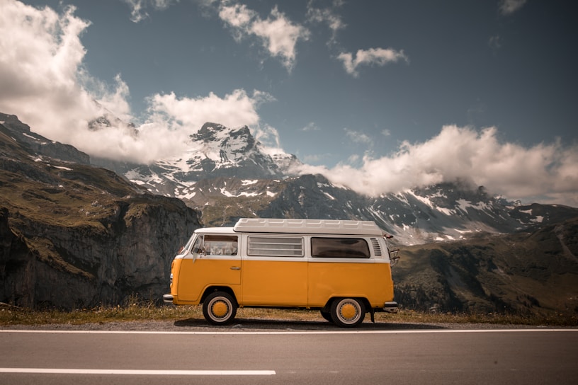 A bright yellow taxi parked by the snow-capped mountains near Manali at sunrise.
