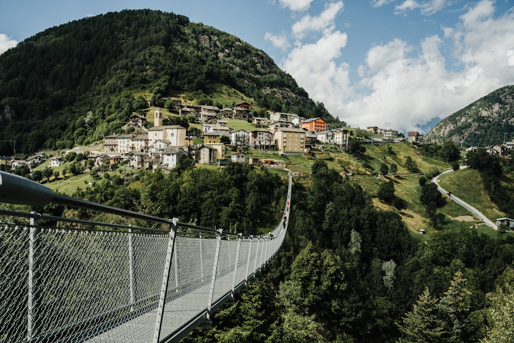 white metal bridge over green mountain during daytime