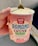 A hand is holding a container of 'Banana Chunk' vegan ice cream by Rewe Beste Wahl. The ice cream features flavors of dark chocolate and walnut pieces. A spoon is inserted into the creamy, light-colored dessert.