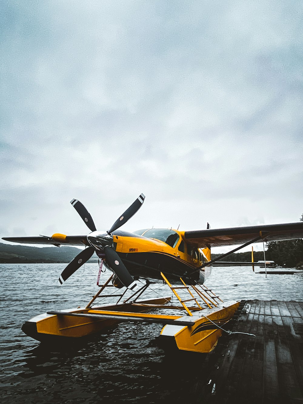 yellow and black plane on dock under white clouds during daytime
