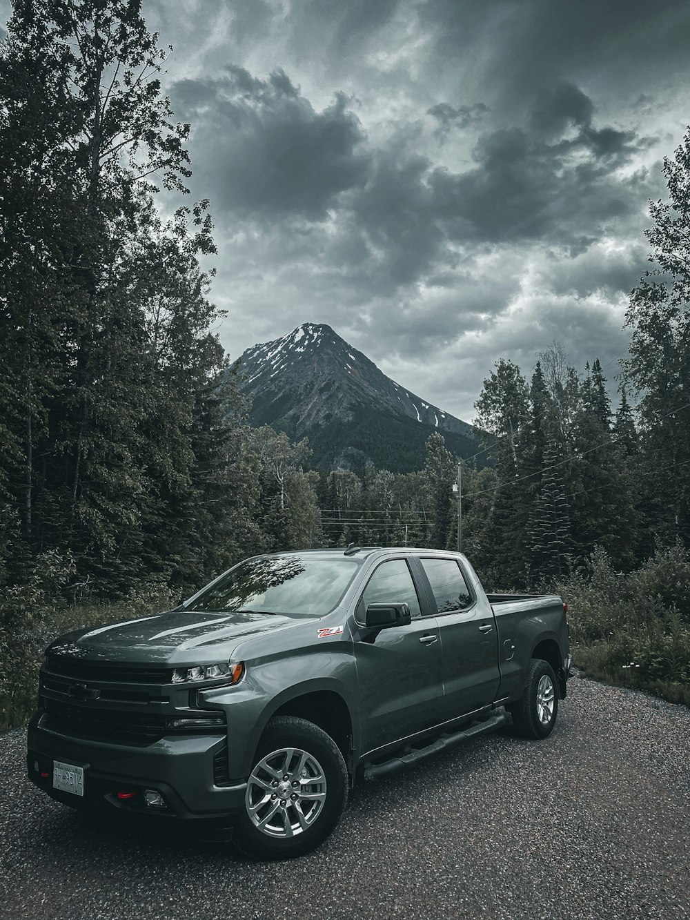 black chevrolet crew cab pickup truck parked on green grass field near green trees and mountain