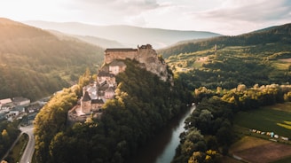 A majestic medieval castle perched on a rocky hill under a golden sunset sky.