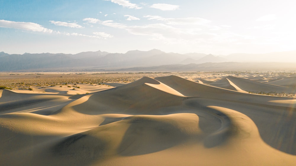 brown sand field under white sky during daytime