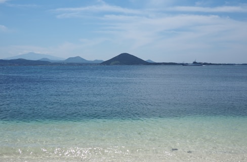 body of water near mountain under blue sky during daytime