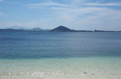 body of water near mountain under blue sky during daytime