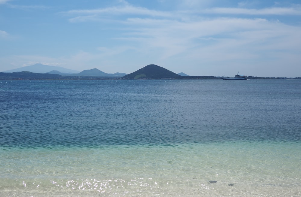 body of water near mountain under blue sky during daytime