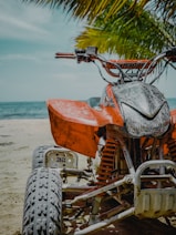 orange and black motorcycle on beach during daytime