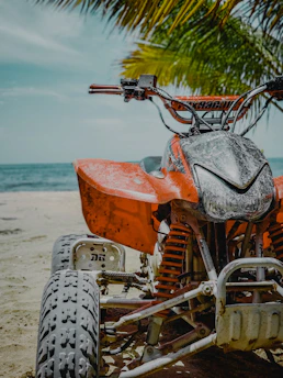 orange and black motorcycle on beach during daytime