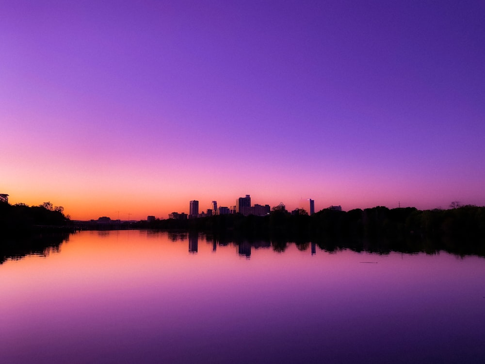 silhouette of building near body of water during sunset