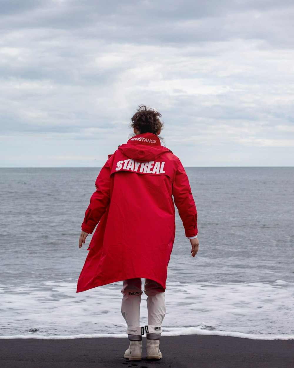 donna in cappotto rosso in piedi su sabbia bianca durante il giorno