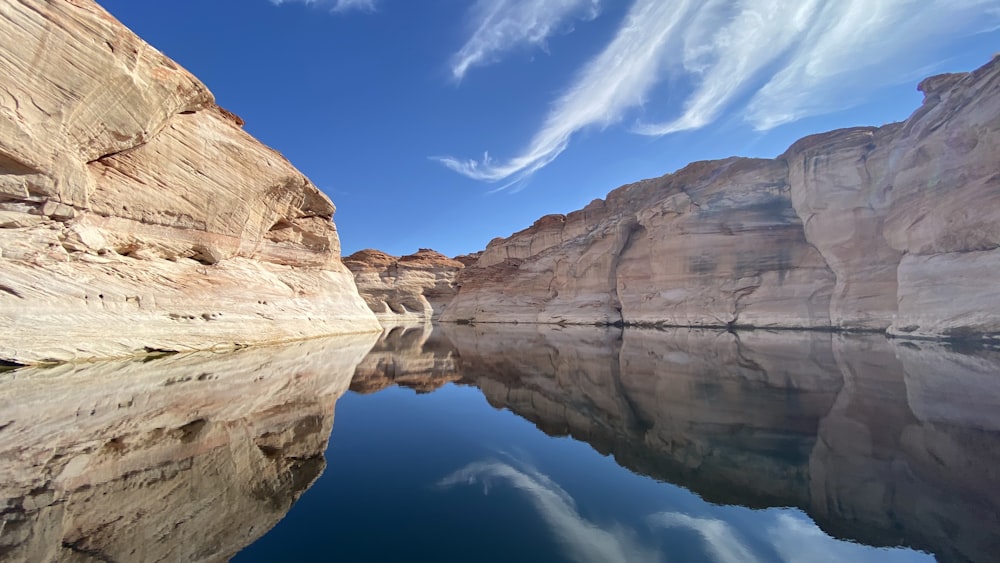 brown rock formation beside body of water under blue sky during daytime