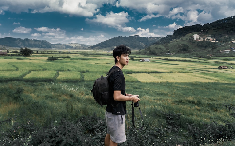 man in black t-shirt and white shorts standing on green grass field during daytime