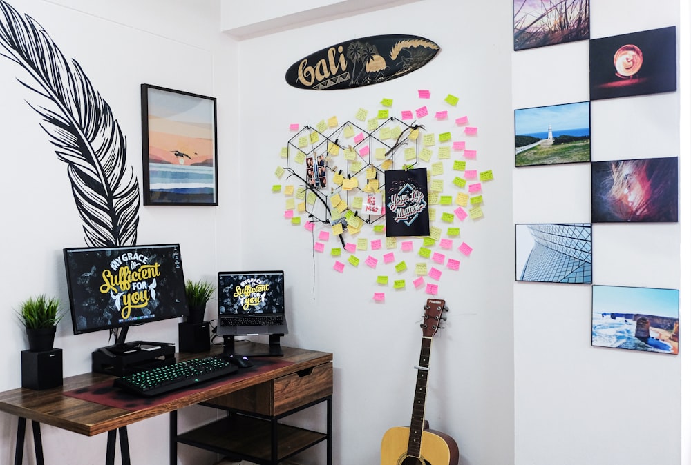a desk with a guitar, keyboard, and various pictures on the wall