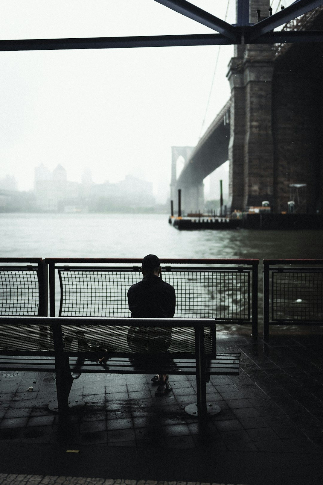 man sitting on bench near body of water during daytime