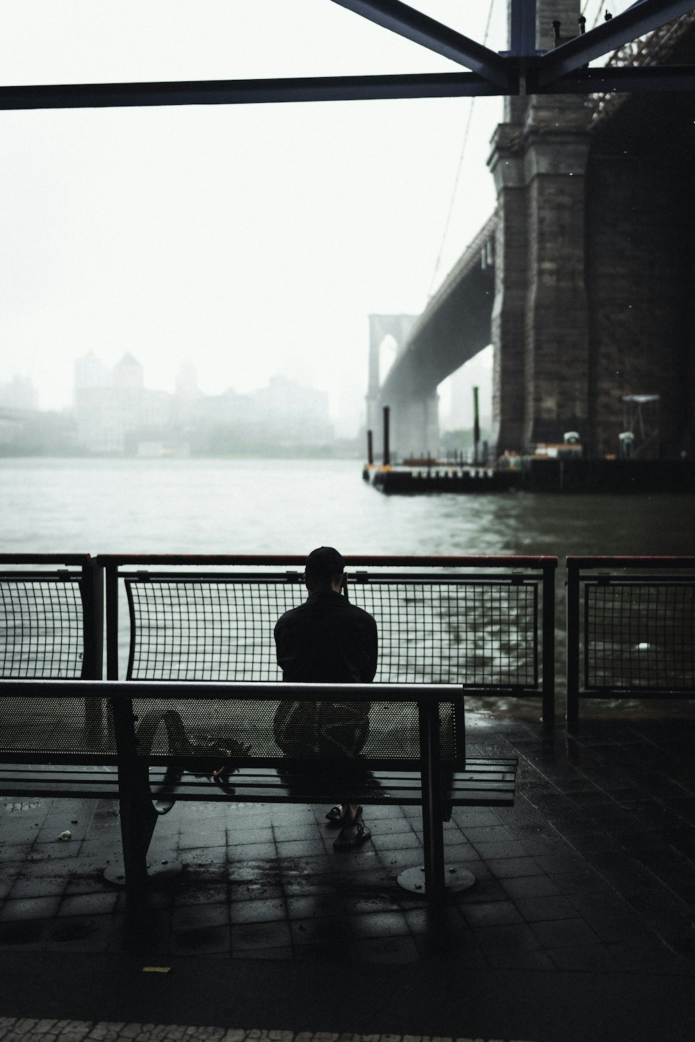 man sitting on bench near body of water during daytime