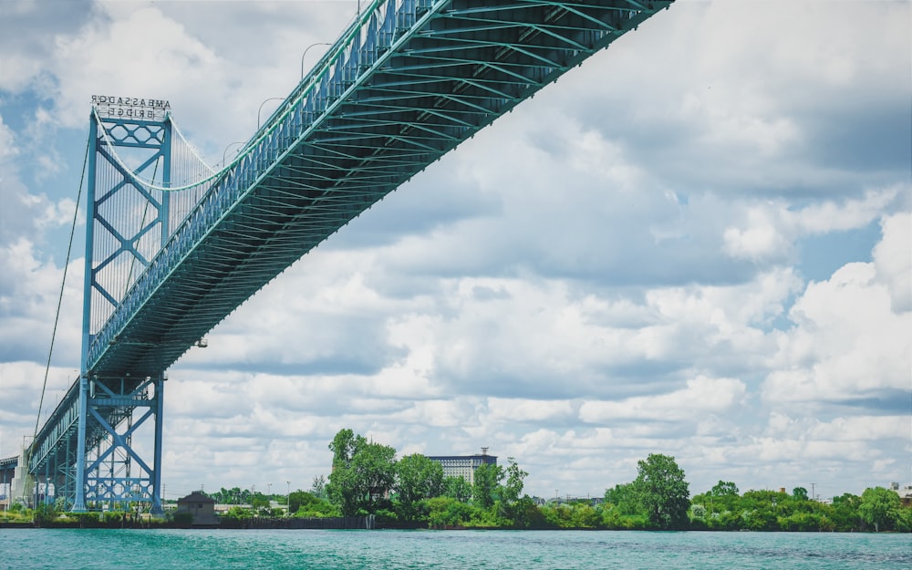 Graue Brücke über Gewässer unter bewölktem Himmel tagsüber