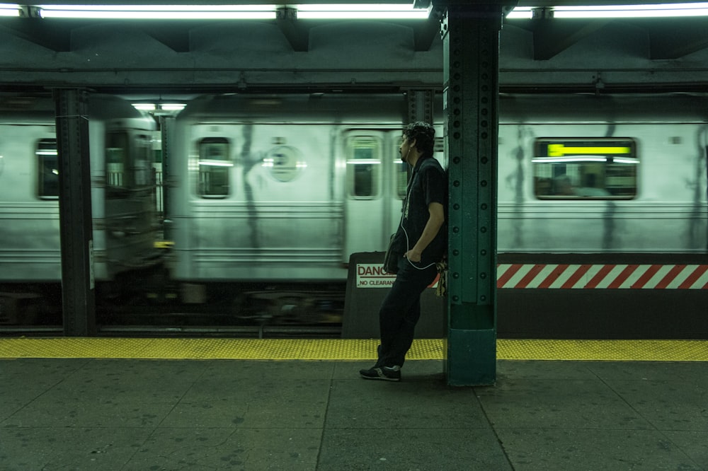 man in black jacket standing beside white train