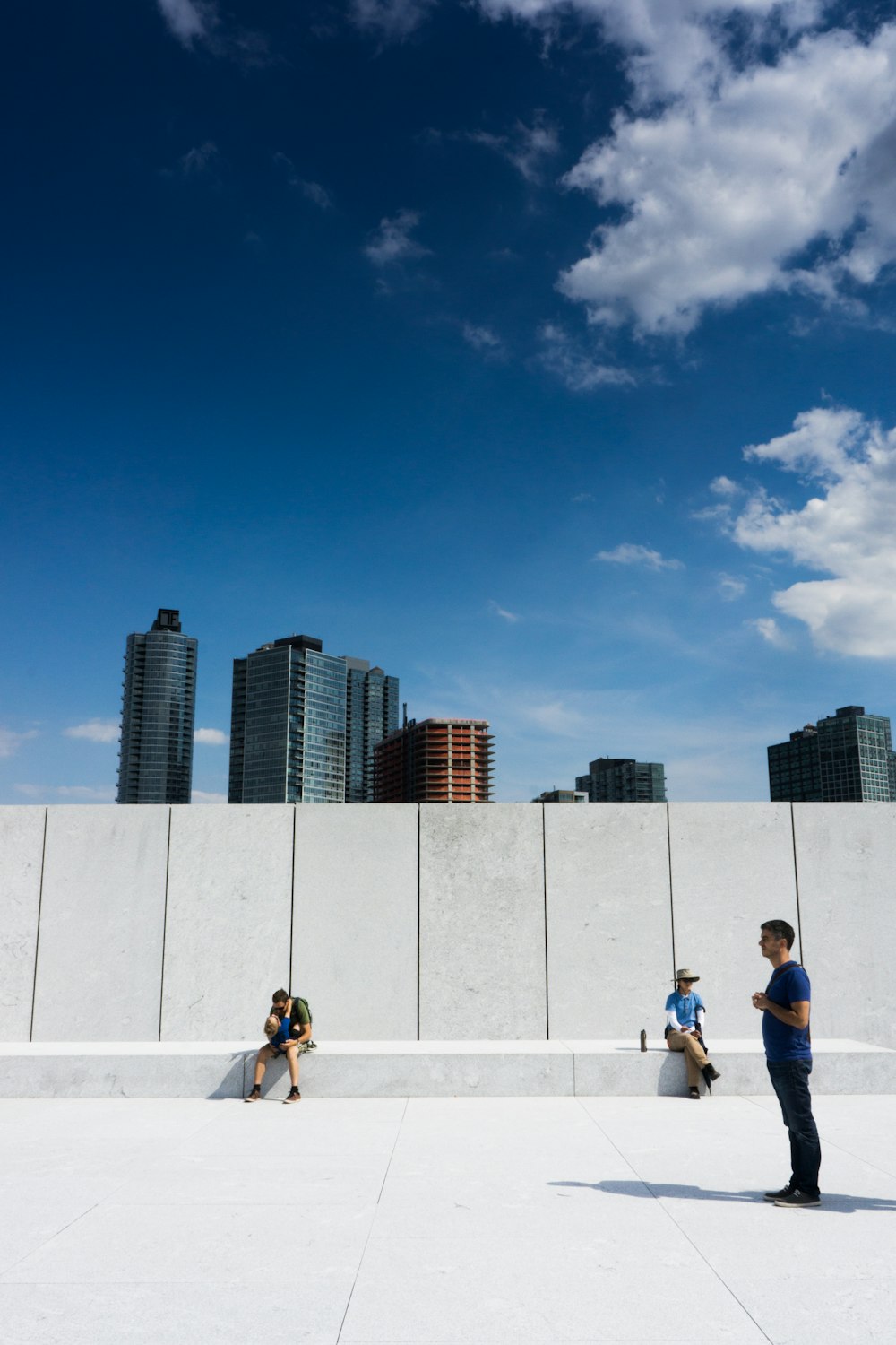 people sitting on white concrete wall during daytime