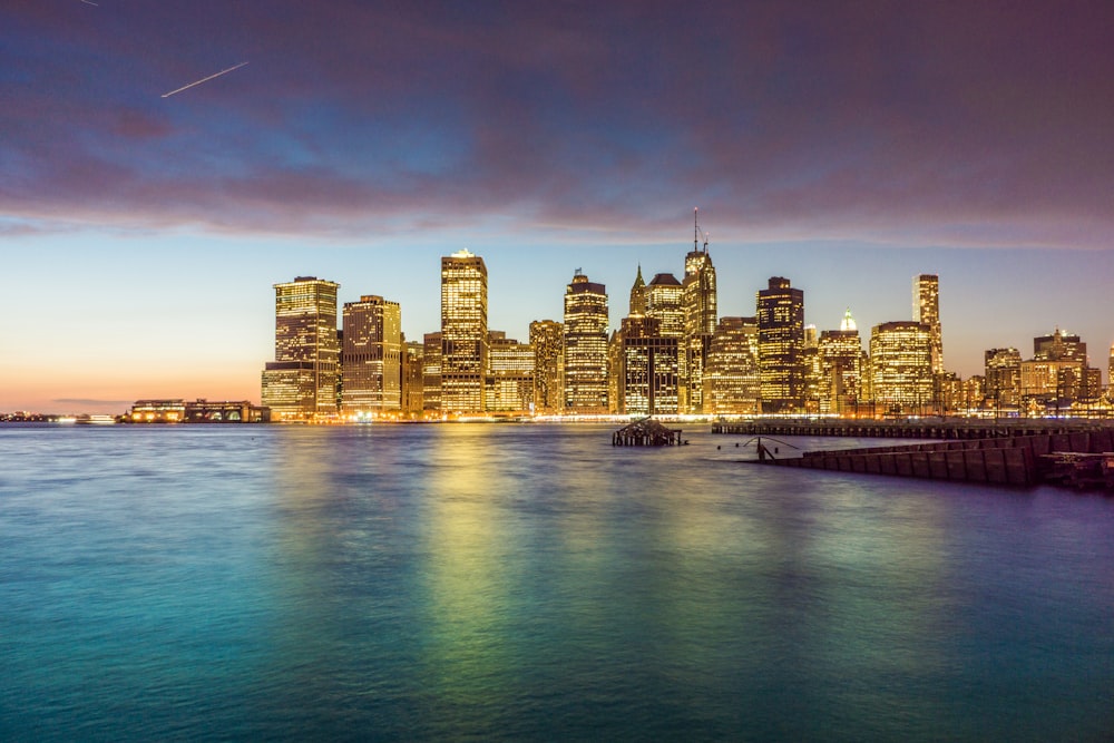 city skyline across body of water during night time