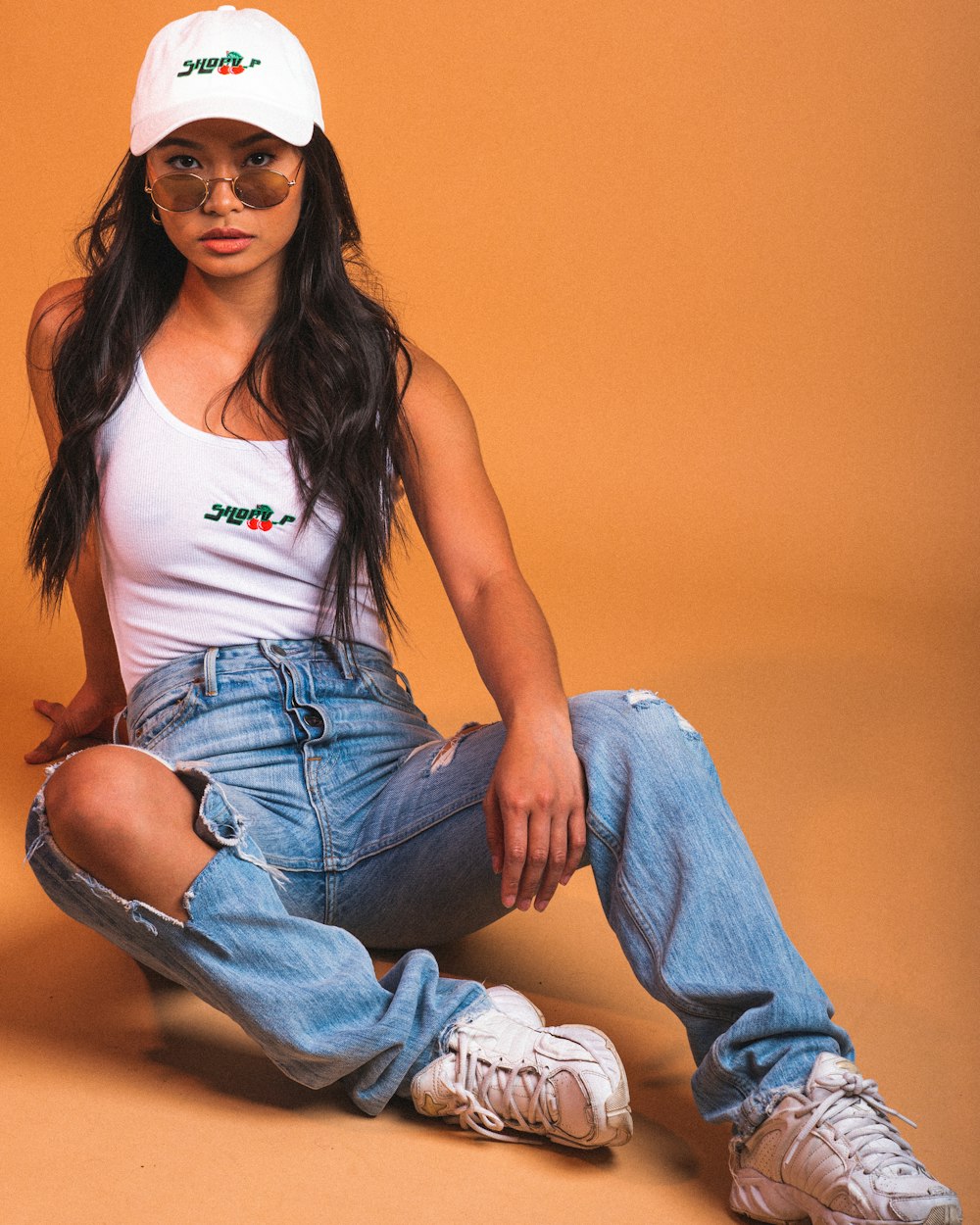 woman in white tank top and blue denim jeans wearing sunglasses