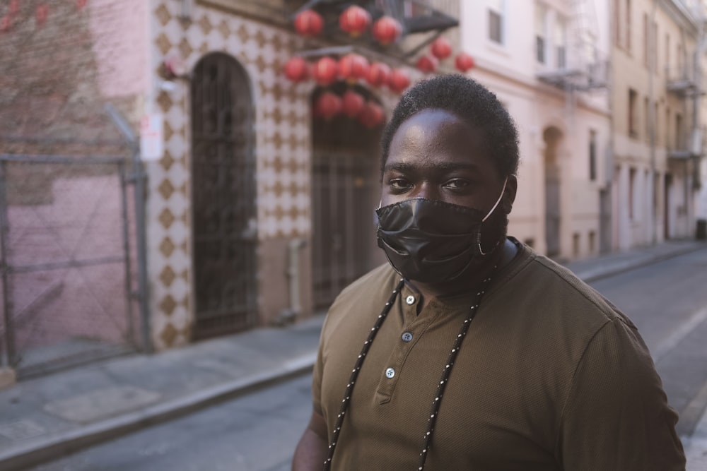 woman in black shirt wearing black mask standing on sidewalk during daytime