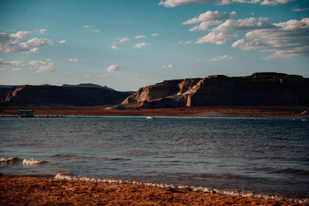 brown mountain beside body of water under blue sky during daytime