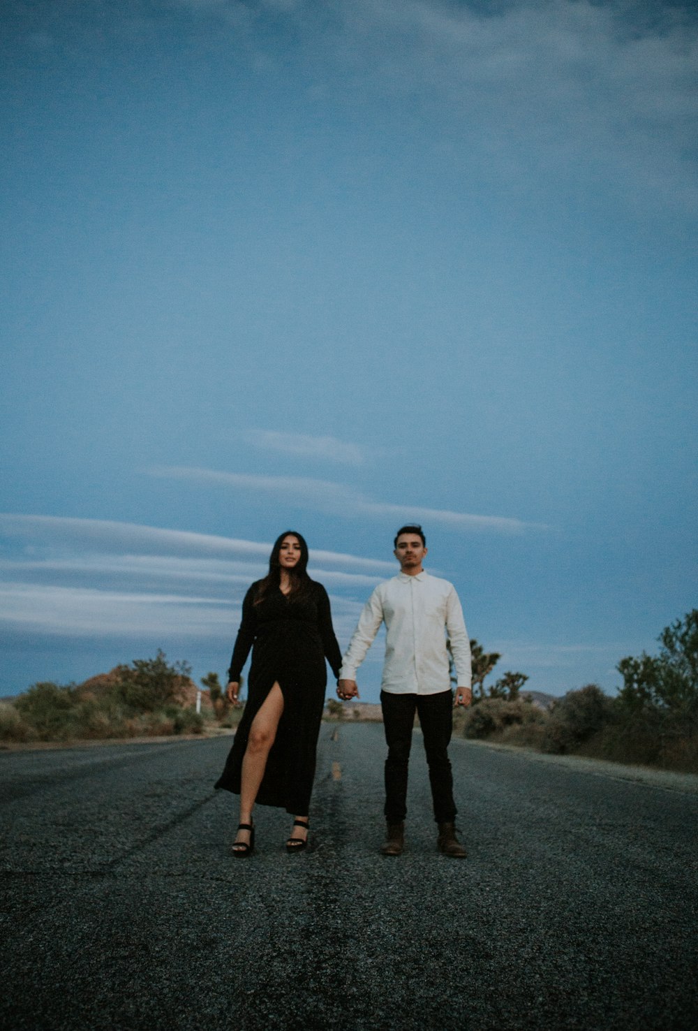 a man and a woman holding hands on a road