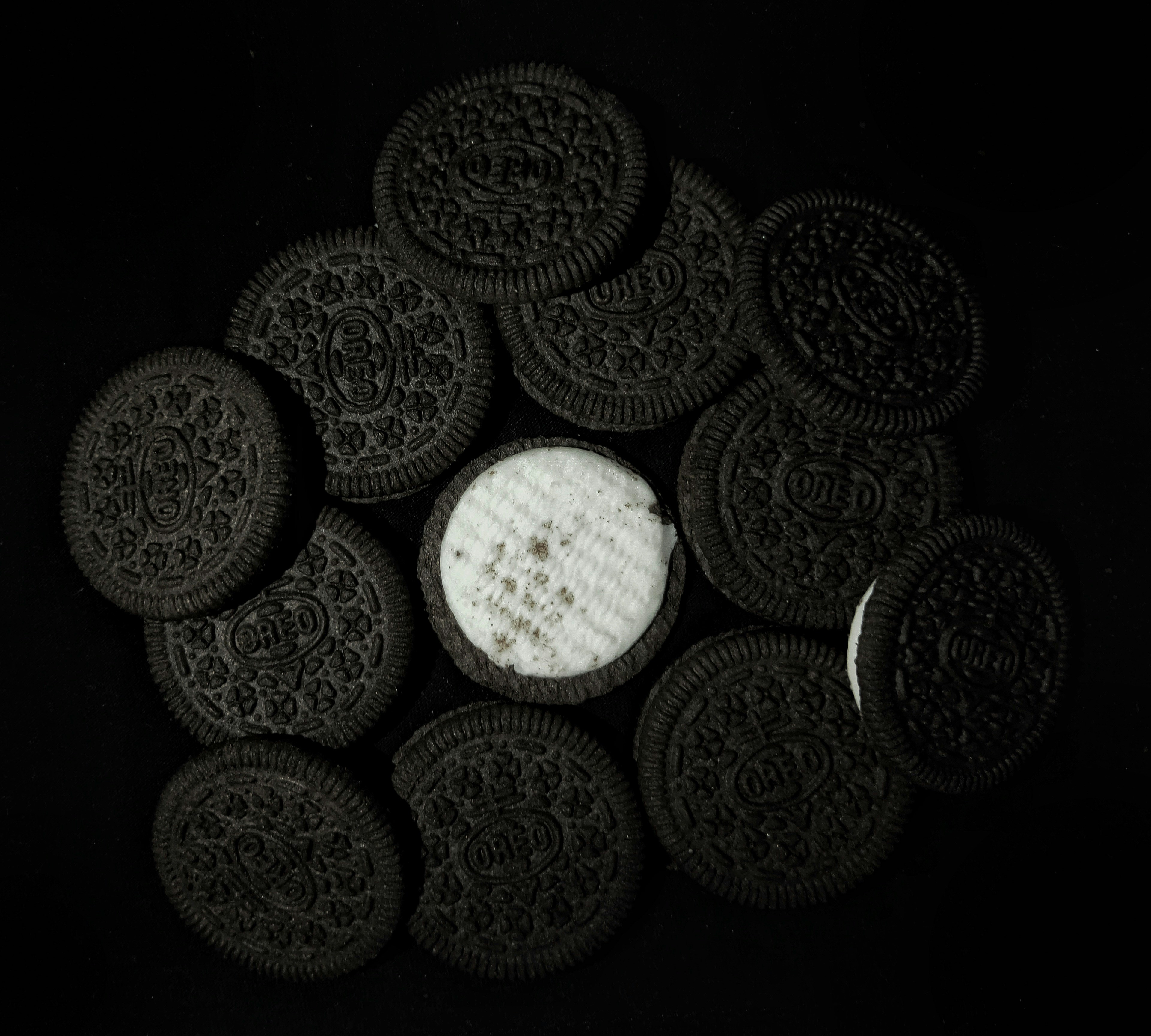 Dessert cup krim Oreo dengan remah cookie hitam, swirl cream cheese putih, latar belakang gelap, pencahayaan studio lembut
