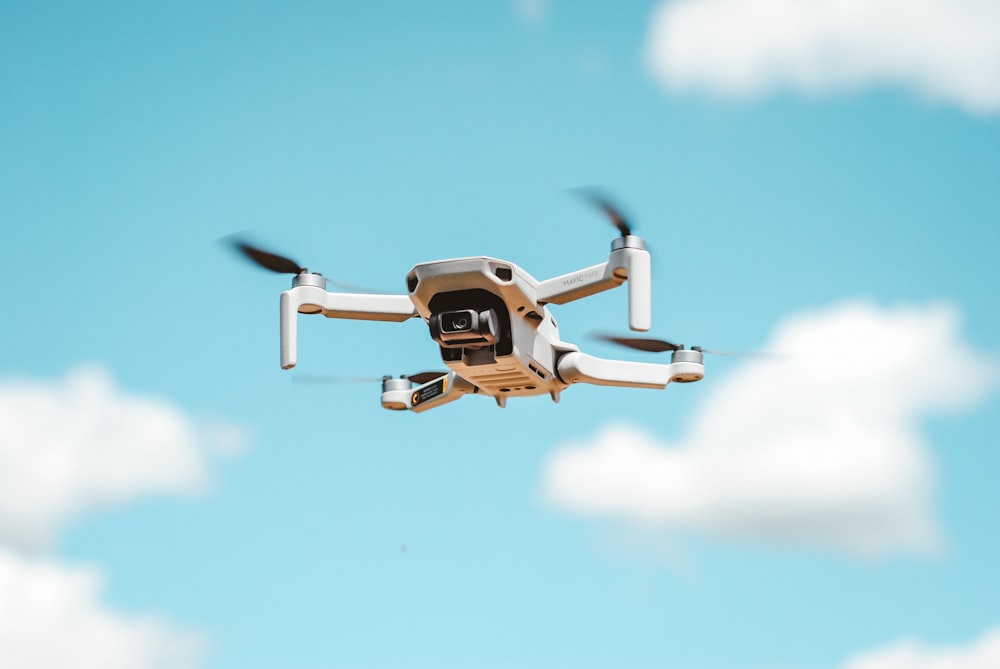 white and black drone flying in the sky