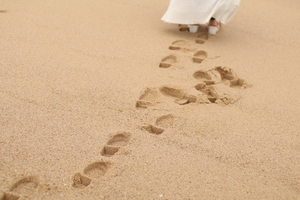 person in white robe sitting on brown sand during daytime