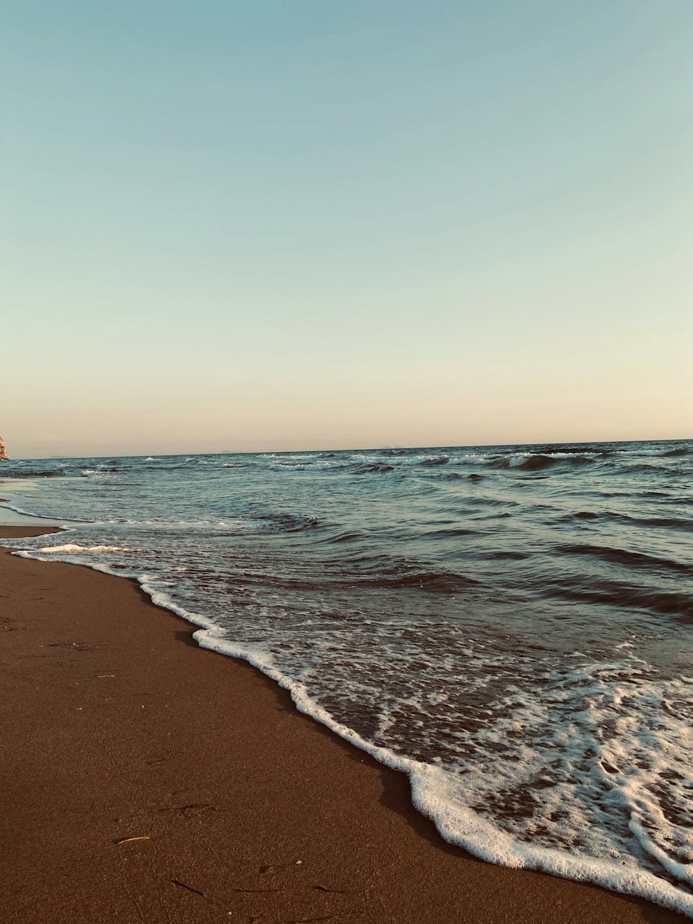 sea waves crashing on shore during sunset