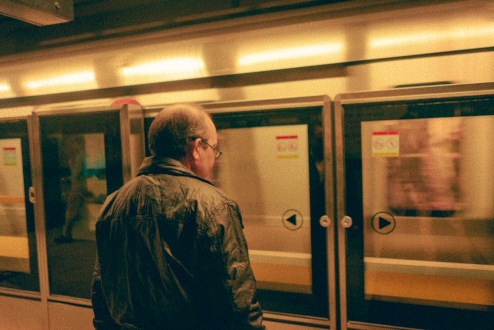 homme en veste noire debout à côté de la porte d’ascenseur argentée